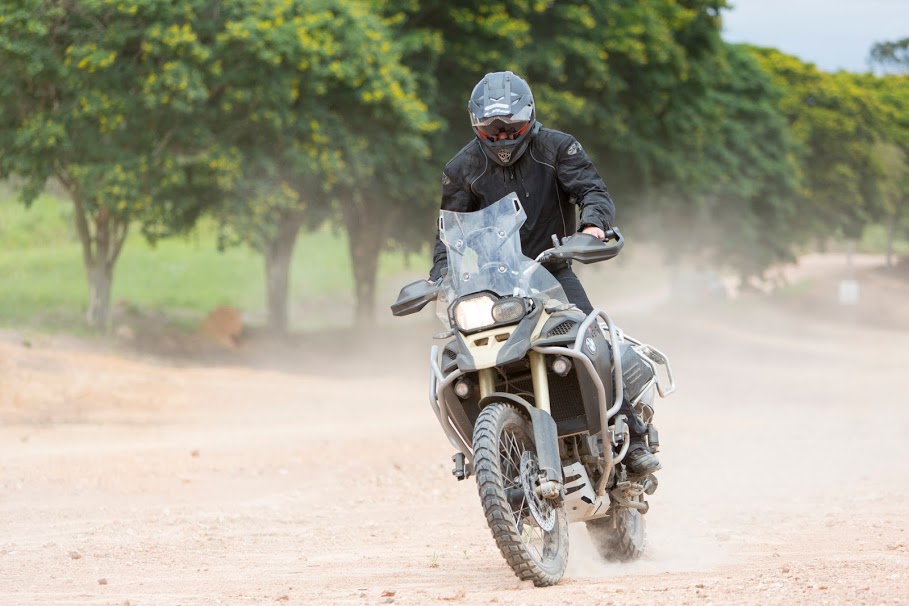 Piloto passando por um terreno off road cercado de árvores